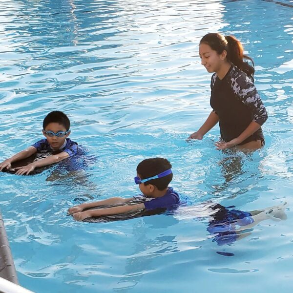 two kids and instructor swimming